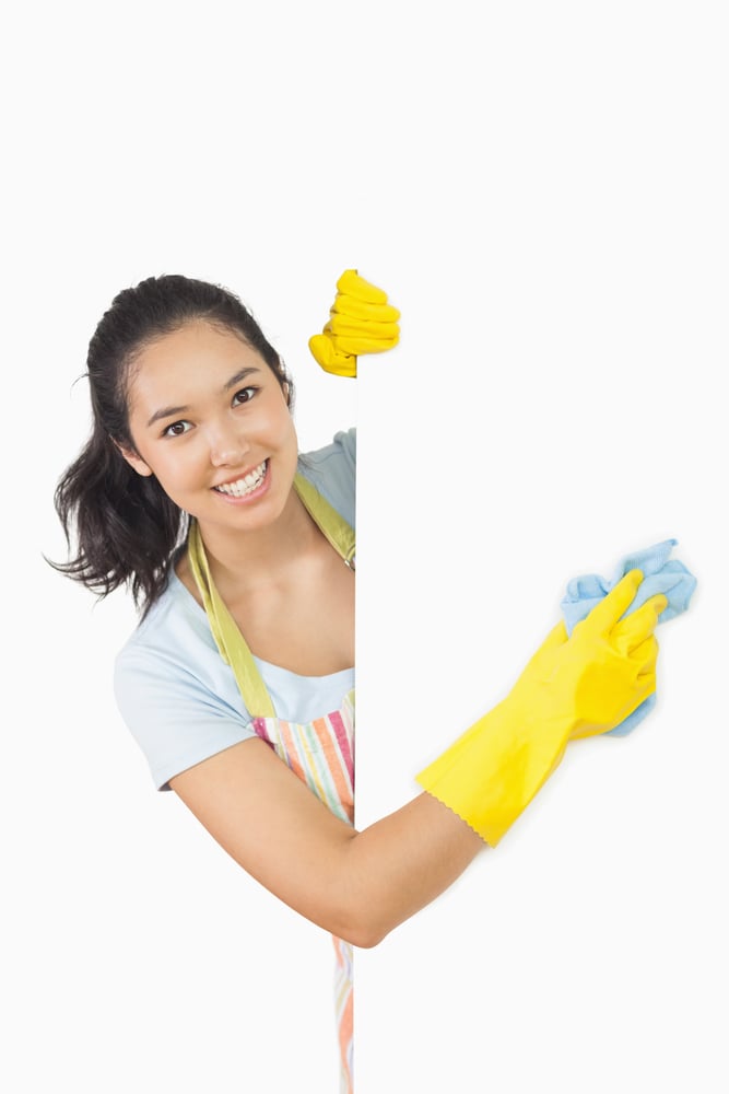 Smiling woman in apron and rubber gloves cleaning white surface-2